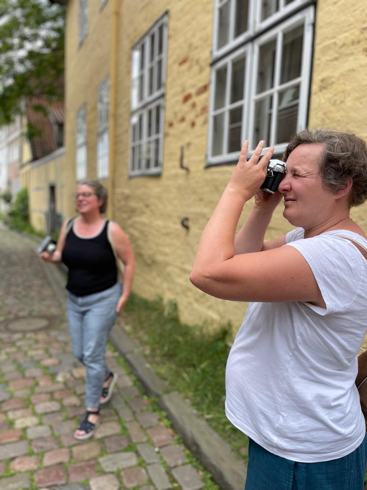 Teilnehmerin blickt durch eine analoge Kamera in einer Lüneburger Gasse