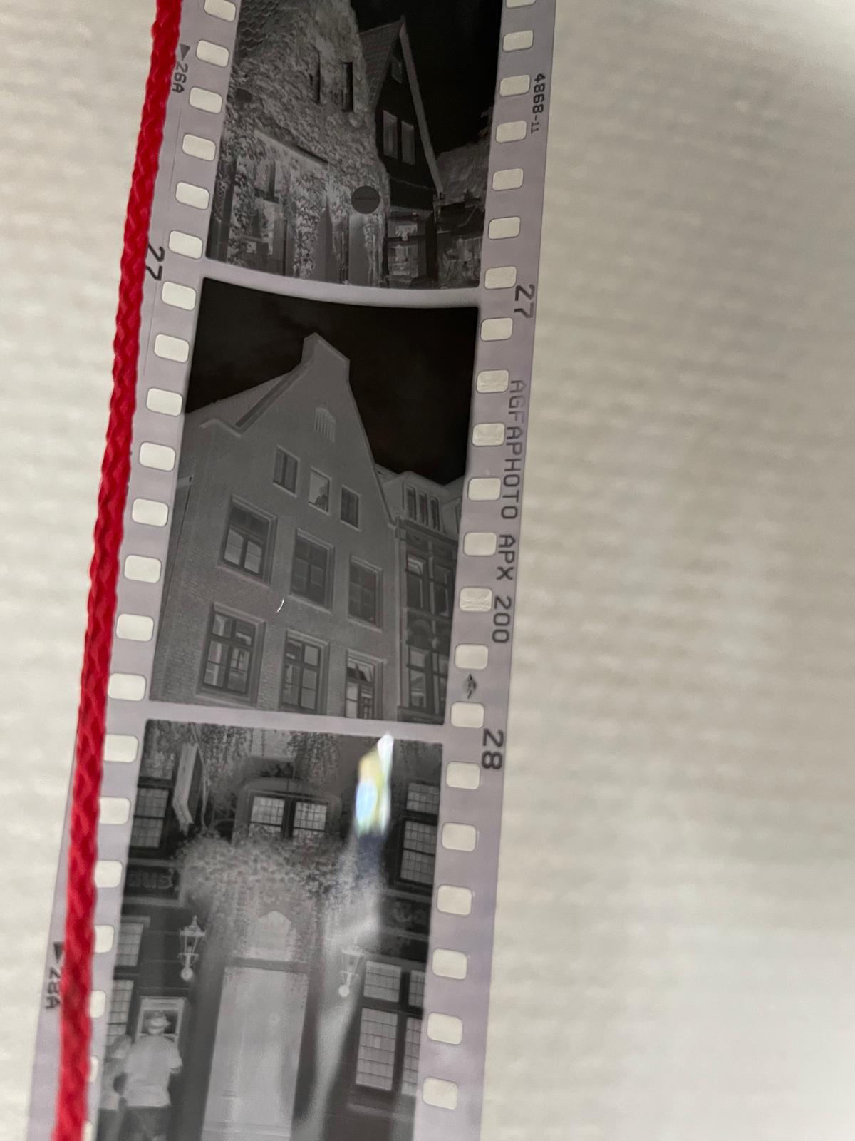 Schwarzweißnegative von Lüneburger Giebeln und Gassen neben einer roten Schnur