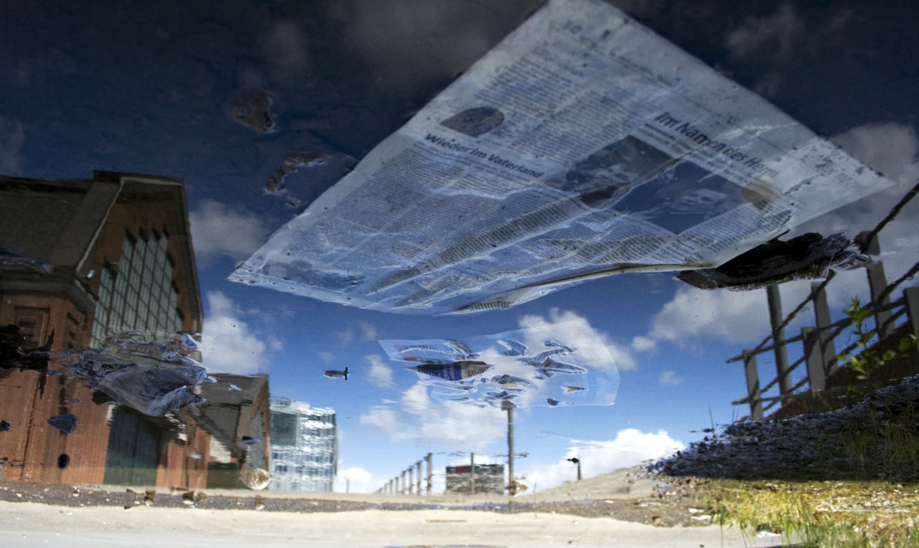 Himmel und Zeitung in einer Wasserreflexion