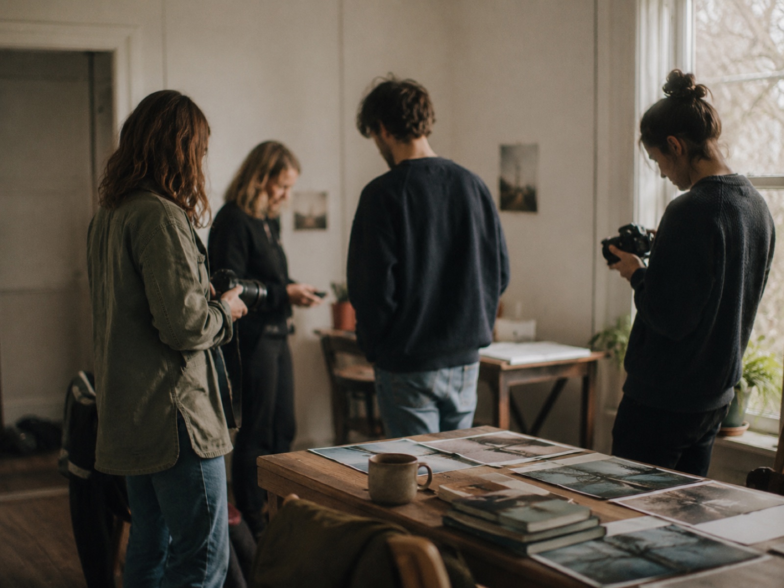 Eine kleine Gruppe betrachtet gemeinsam Fotografien auf einem Tisch